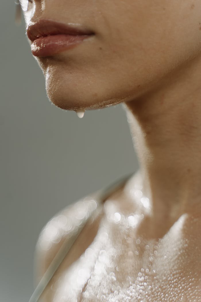 Close-up shot of a woman's face and shoulder with water droplets, capturing the essence of freshness and purity.